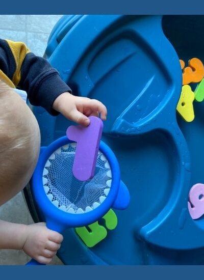 Image of toddler playing with numbers in water table for number recognition